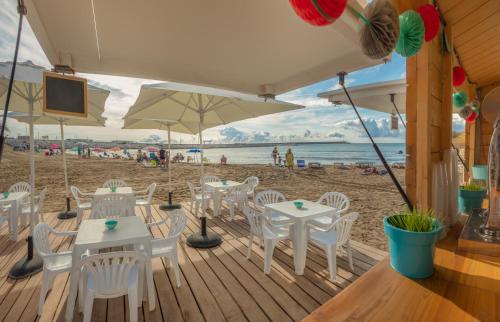 a wooden deck with white tables and chairs on the beach at Hotel RH Vinarós Aura in Vinaròs