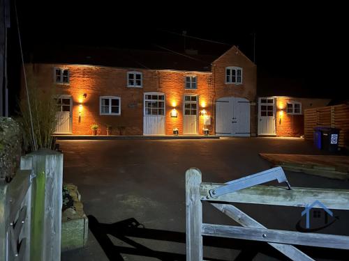 an empty parking lot with a brick building with white doors at Coach House at The George Pub, Ashley, Market Harborough in Ashley