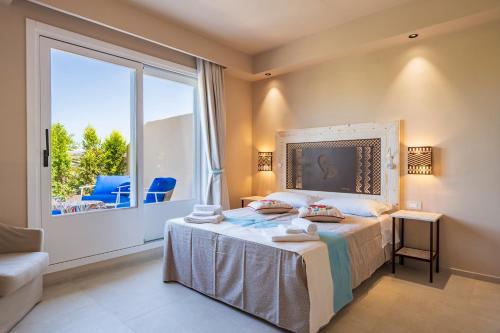 une chambre avec un lit et une grande fenêtre dans l'établissement Sogno, à Tortolì