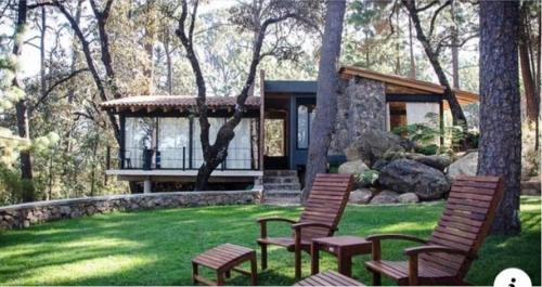 a house with three chairs in the grass at Xomue in Valle de Bravo