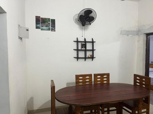 einen Esstisch mit Stühlen und einen Ventilator an der Wand in der Unterkunft Tulips villa in Mānantoddy