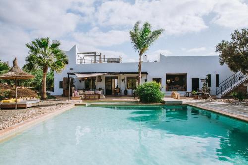 a villa with a swimming pool in front of a house at Les jardins de Silona, piscine chauffée in Essaouira