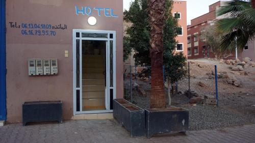 um hotel com uma árvore em frente a um edifício em Hotel adrar em Tafraoute