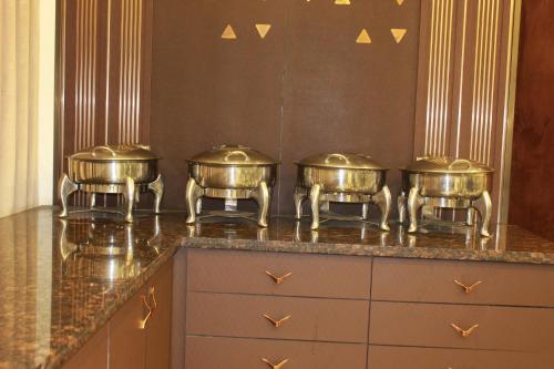 Un grupo de cuatro ollas en una encimera de cocina. en Hotel Planet Four, en Lonavala