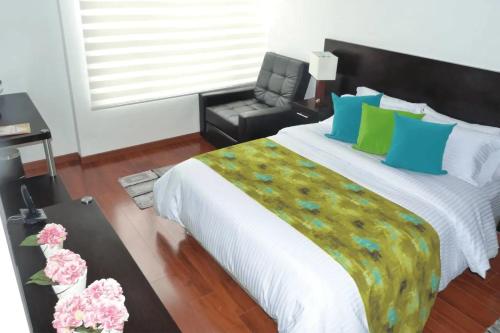 a bedroom with a large bed with blue and green pillows at Hotel Laverdieri in Suba