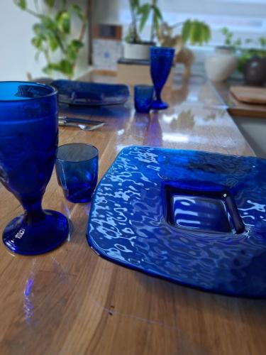 a wooden table with blue plates and glasses on it at Hôte Stéphanois Studio & parking in Saint-Étienne