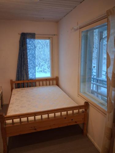 Traditional Finnish Lapland house at wild forest backyard! في كيمي: غرفة نوم صغيرة بها سرير ونافذة