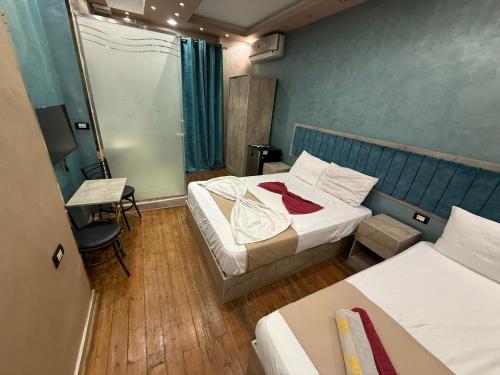 Una pequeña habitación con dos camas y una mesa y una cama cuadrada. en The-Cairo Plazario Downtown Hotel, en El Cairo