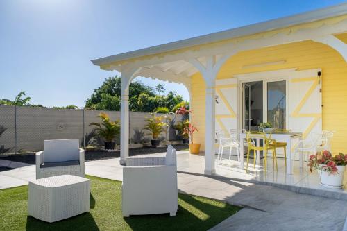 a yellow house with white chairs and a patio at Villa Guenaslo 1 in Saint-François