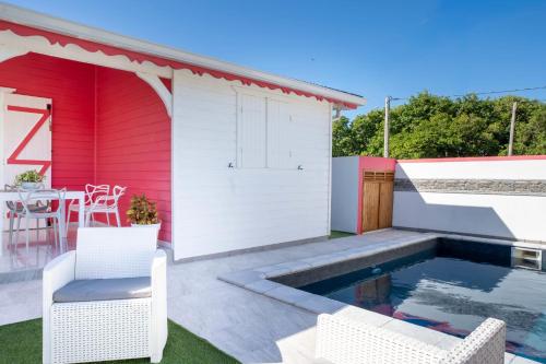 a red and white house with a swimming pool and two chairs at Villa Guenaslo 2 in Saint-François