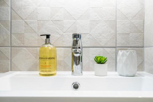 a bottle of alcohol sitting on a bathroom sink at Enigma Lodge in Stratford-upon-Avon