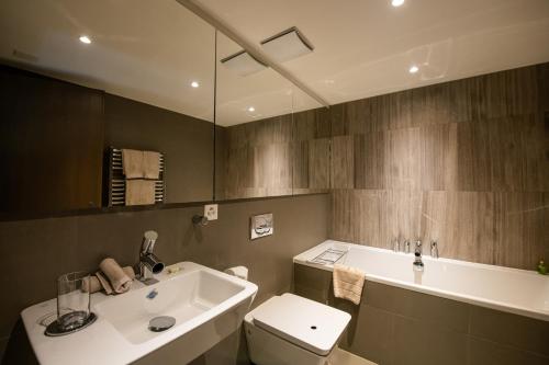 a bathroom with a sink and a toilet and a tub at Chalet RoyAlp Hôtel & Spa in Villars-sur-Ollon