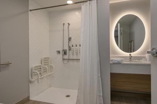 a white bathroom with a shower and a mirror at TownePlace Suites by Marriott Miramar Beach Destin in Destin