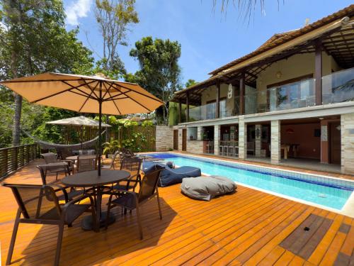 a wooden deck with a table and umbrella next to a swimming pool at Villa Maritaca Condomínio de 4 Casas de Locação por Temporada de Alto Padrão com SPA in Arraial d'Ajuda