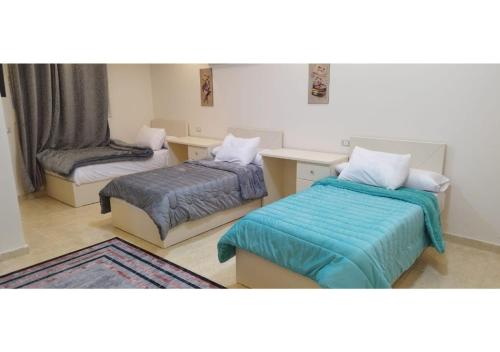 a room with two beds and a chair at رويال للغرف الفندقية in Mît Khamîs