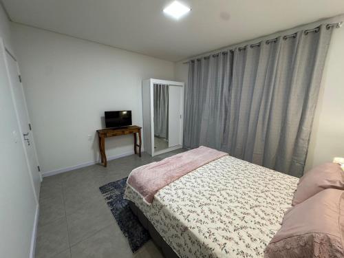 una camera con letto, specchio e TV di Casa Nova & Aconchegante a São Bento do Sul