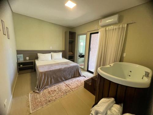 um quarto com uma cama e uma banheira em Recanto Catarina em Cascavel