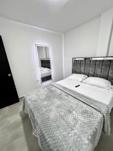 a white bedroom with a large bed and a mirror at GM Suites in Cúcuta