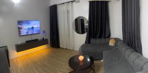 een woonkamer met een bank en een flatscreen-tv bij Sweet Dream Apartment in Lekki