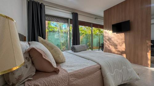 Un dormitorio con una cama grande y una ventana grande. en Pipa de oliveiras, en Pipa