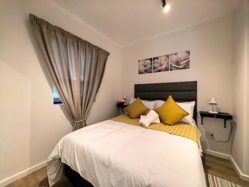 a bedroom with a bed with yellow pillows and a window at Luxury Apartment Unit 111 Le Jardin in George