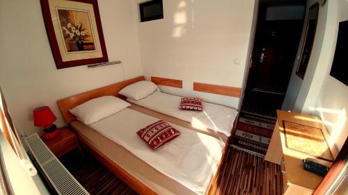 a small bedroom with a bed with two pillows at Pansion River in Sarajevo
