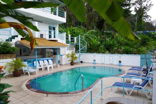 a pool at the hotel with chairs and trees at Residy Retreat x Baan Suan Villa in Patong Beach