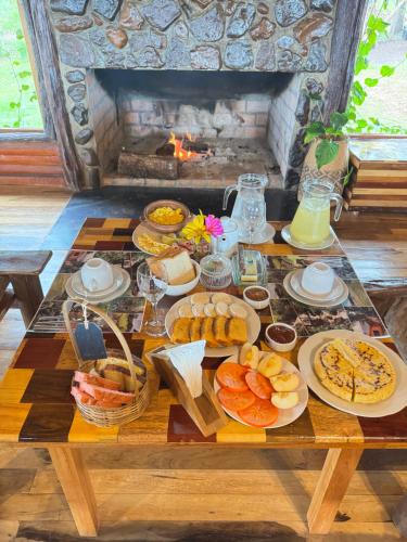 a table topped with plates of food next to a fireplace at Piedra y Agua Cabañas & Ecolodge El Soberbio Misiones Saltos del Moconá in El Soberbio