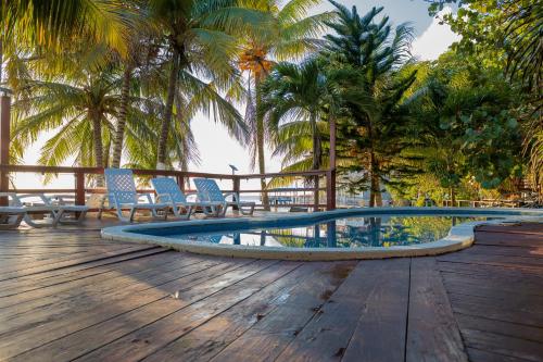 a pool on a wooden deck with chairs and palm trees at West Bay Room, Pool, Fridge, Shuttle, Dive in West Bay