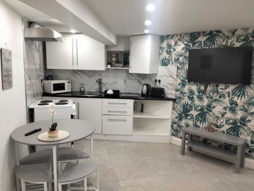 a kitchen with a table and a tv on the wall at Modern 3-bed Serviced Appartement - Milnsbridge in Lindley
