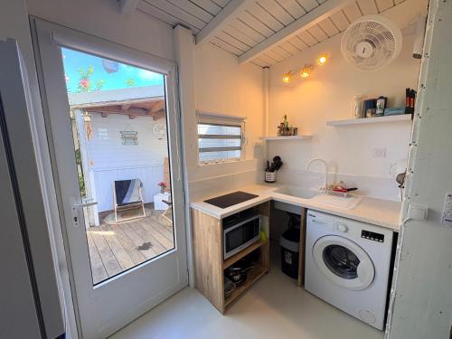 uma pequena cozinha com uma máquina de lavar roupa e uma janela em Studio sucrier 150m des plages orient bay em Orient Bay