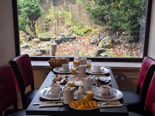 Ein Tisch mit Frühstücksspeisen und Blick auf einen Wald in der Unterkunft Boutique HOTEL am KRANICHSEE in Hahnenklee-Bockswiese