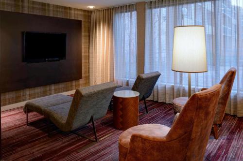 a hotel room with chairs and a flat screen tv at Sonesta Select Kansas City Airport Tiffany Springs in Kansas City