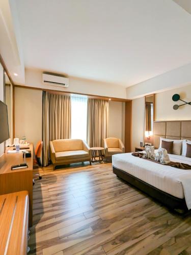 a hotel room with a large bed and a living room at Astanaraya Suites Hotel in Jakarta