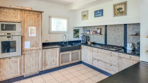 a large kitchen with wooden cabinets and a sink at MY Tropézienne in Saint-Tropez