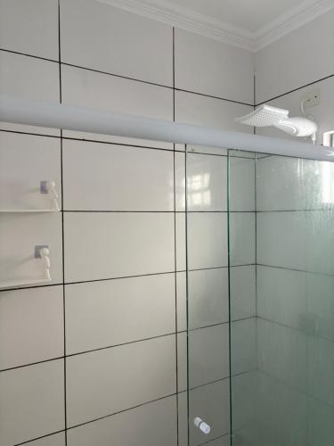 a glass shower in a bathroom with a white wall at Casa próximo à rodoviária e centro in Rondonópolis