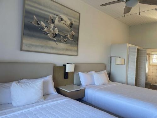 een slaapkamer met twee bedden en een schilderij aan de muur bij Queen Deluxe Double at Boundless Bliss Hotel in Raphune