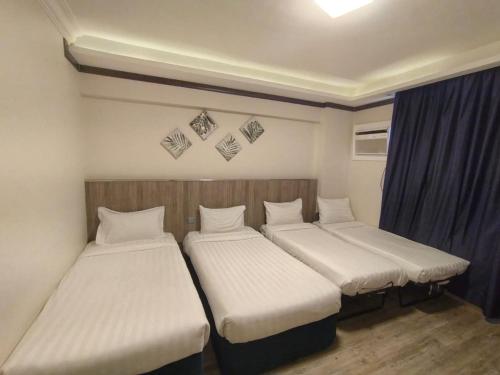 a room with three beds in it with curtains at Hayat Al madinah Hotel فندق حياة المدينة in Al Madinah