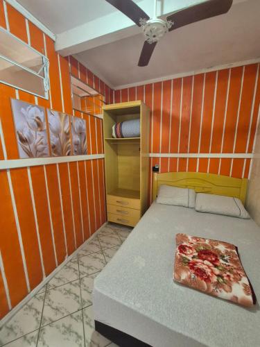 a room with a bed with an orange wall at Casa em Ganchos in Governador Celso Ramos