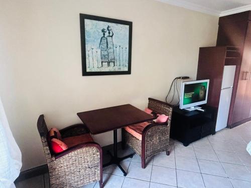 Una habitación con una mesa y sillas y un televisor. en Ocean View Villas B09, en Port Edward