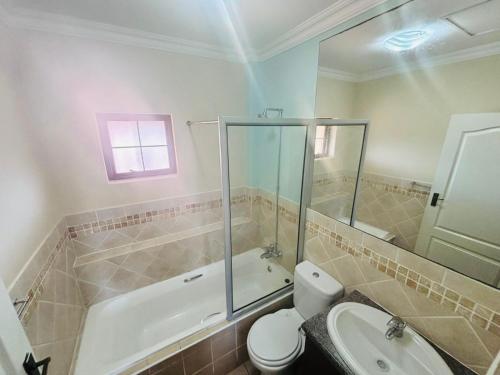 Un baño con inodoro, ducha y lavabo. en Ocean View Villas B09, en Port Edward