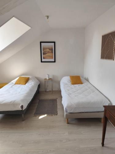 Duplex spacieux et lumineux en centre-ville في شاتودون: سريرين في غرفة بجدران بيضاء