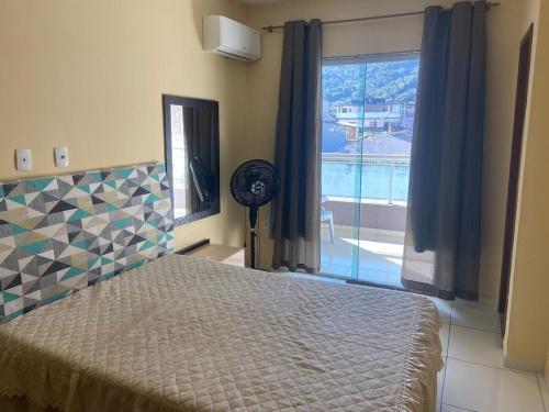 a bedroom with a bed and a window and a fan at Sabrina · Duplex com excelente localização, em Muriqui in Mangaratiba