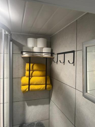 a bathroom with yellow towels on a shelf at Kaira's Nook in Wolverton