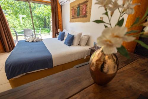 1 dormitorio con 1 cama y un jarrón con flores en San Francisco Lodge, en Los Andes