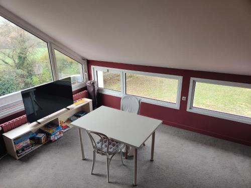 a room with a table and a tv and windows at Gite du bout là haut in Audincthum