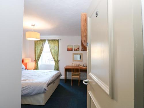 een slaapkamer met een bed en een bureau met een tafel bij Bedroom 2 in Wolsingham