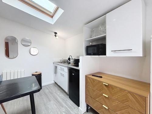 eine Küche mit weißen Schränken und schwarzen Geräten in der Unterkunft Le Jardin Secret Apartment in Montbéliard