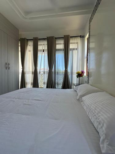 ein großes weißes Bett in einem Schlafzimmer mit Fenster in der Unterkunft Etheria Haven in Mombasa