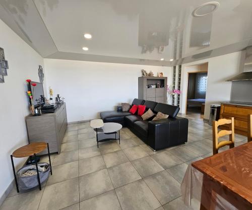 a living room with a black couch and a kitchen at Paradiso Apartment 4 people in Furiani